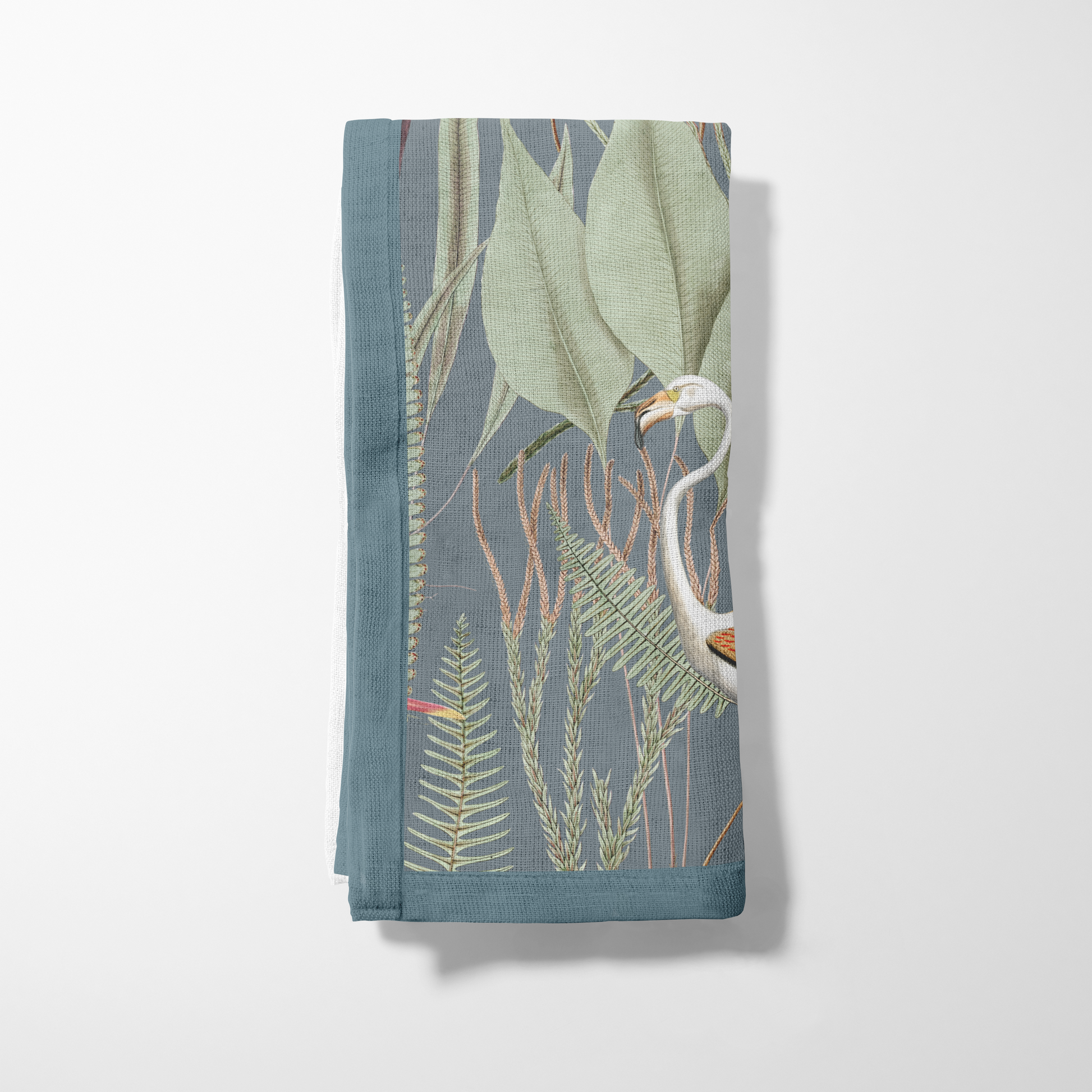 Folded fabric with a nature-themed design featuring plants and a bird on a light gray background